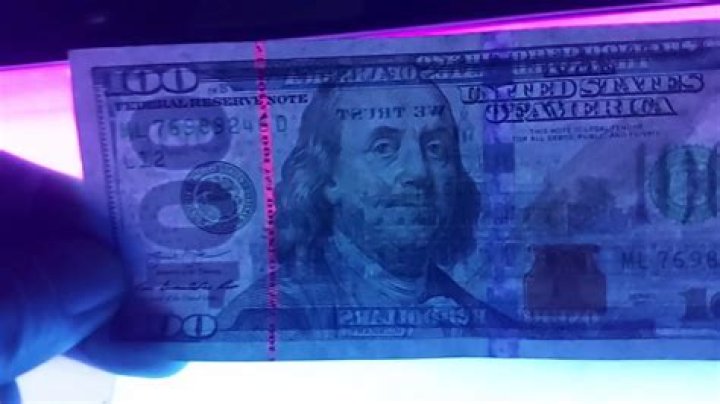 Why do some dollar bills glow under black light?
